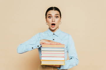 shocked student in denim shirt with books on beige