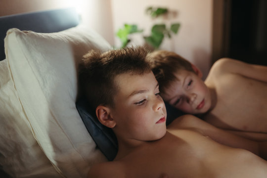 Kids enjoying reading ebook in cozy bedroom.