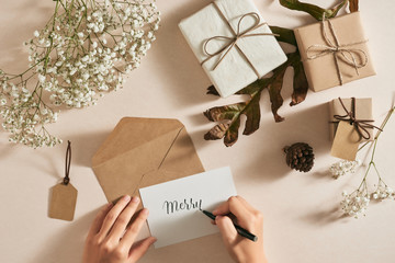 Female hands holding pen going to write letter on a piece of craft paper at Christmas. Top view.