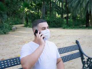 Fototapeta premium Hombre joven usando el smartphone con una mascarilla en la boca