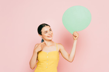 brunette young woman with green blank speech bubble on pink