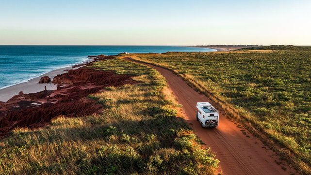 camping truck on corrugated road beside ocean