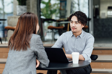 Businessman and businesswoman sitting in cafe and using laptop