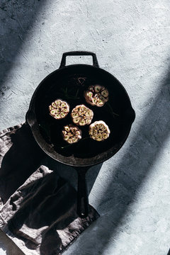 Garlic cloves with rosemary in cast iron