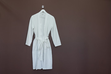 New white bathrobe isolated on brown background