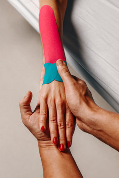 Physiotherapist using kinesiotaping techniques on woman arm