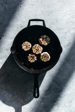 Garlic cloves with rosemary in cast iron