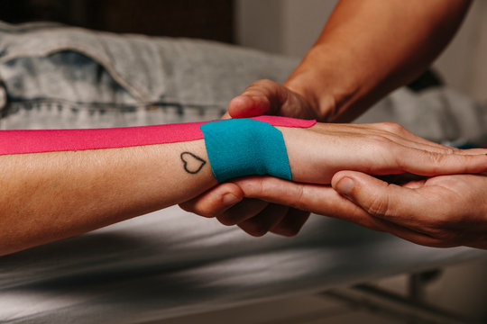 Physiotherapist using kinesiotaping techniques on woman arm