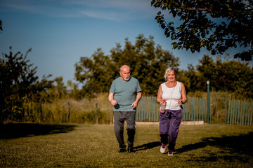 Senior couple running outside . Elderly man and  woman jogging together