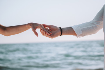 Manos en la playa con el mar de fondo, novios el dia de boda