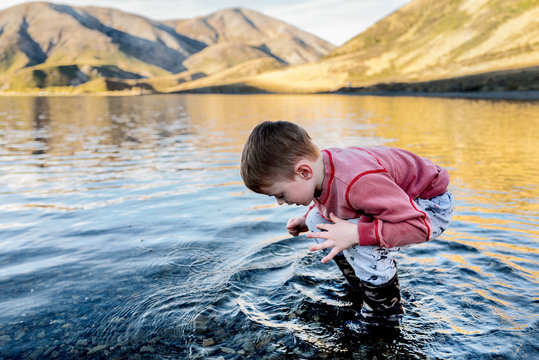 Child searching the shallows of a mountain lake