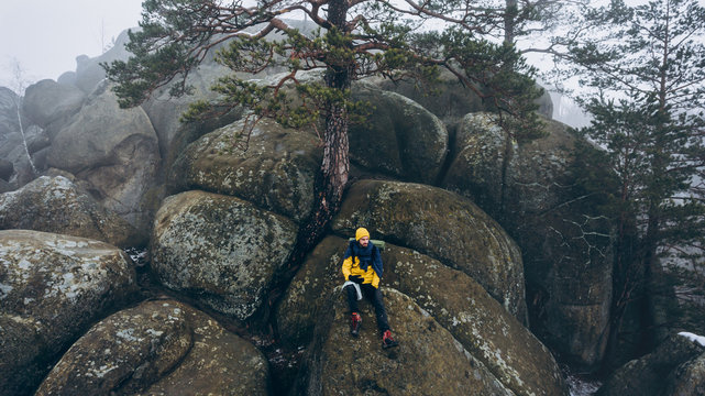 Climber sitting on large rocky stones and enjoying beautiful landscape.
