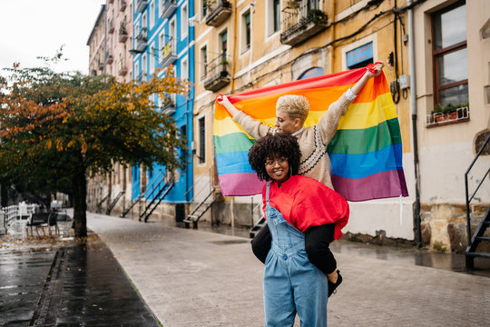 Two women carrying a LGTB flag at street