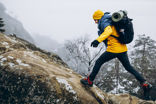 Climber hiking to peak of rocky snow mountains