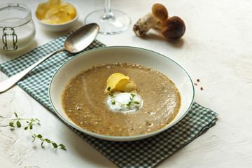 Mushroom cream soup in a white plate, with creamy foam and chips. On a white surface with space