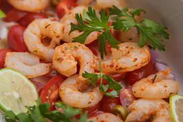 fresh raw peeled prawns with sliced cherry tomatoes, herbs and spices.