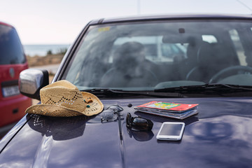Mapa,sombrero y smartphone encima del capo del coche
