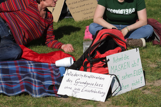 Sitzende Teilnehmer mit Plakaten an einer Corona-Demonstration gegen Maskenpflicht in Deutschland