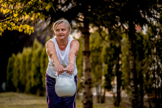 Senior Woman Exercising With Kettle Bell Outdoors