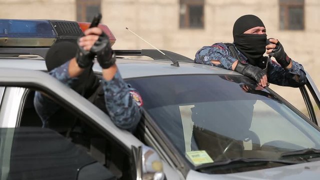 Police special forces surround a building with terrorists. Special armed police on radio by car.