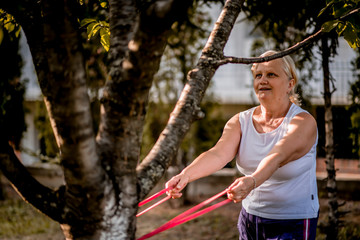 Senior woman exercising with elastic band outdoors 