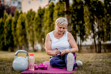 Senior woman with diabetes checking her blood glucose using  glucose meter