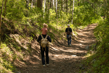 Father walks along a forest trail with his little daughter