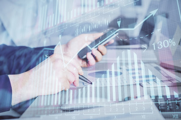 Double exposure of man's hands holding and using a digital device and forex graph drawing. Financial market concept.