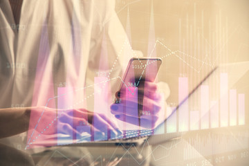 Double exposure of financial graph sketch hologram and woman holding and using a mobile device. Stock exchange concept.