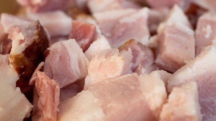 Smoked bacon meat with lots of fat on it, carved and diced on a wooded board.
The meat is salt-cured and from a pig's belly or back.