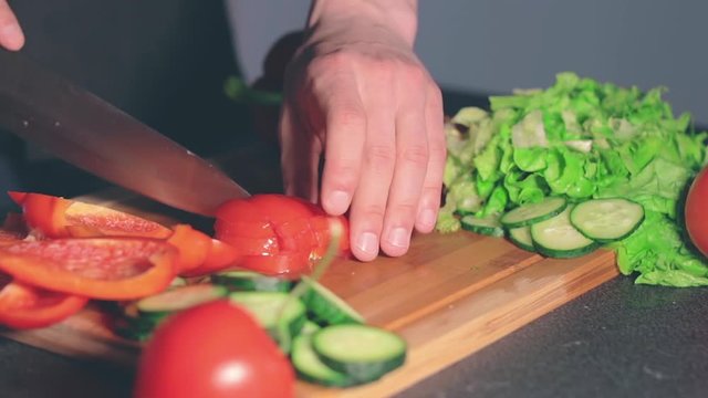 Chef in Blach Uniform is Cutting Vegetables at Home. Cook is Preparing Ingredients for Something Dietary. Healthy Food Concept. Dynamic Closeup Shot