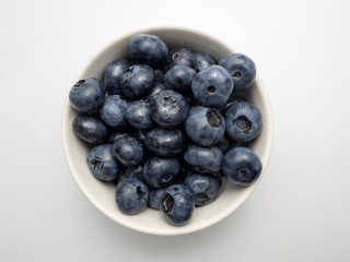 A true overhead shot of blueberries in a small white bowl.