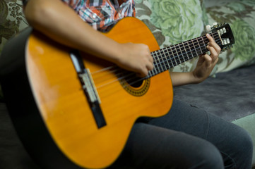 Acoustic guitar, the hands of a young musician play the guitar.