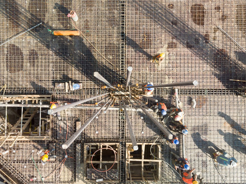 Vista a&eacute;rea cential sobre el armado de una columna en una obra en construcci&oacute;n con obreros trabajando en segundo plano.