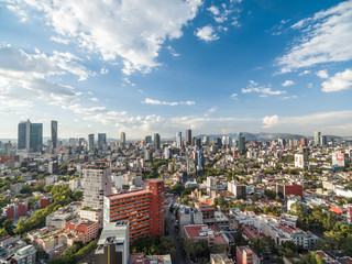 Vista aérea panorámica de la Ciudad de México sobre la Colonia Roma con vista al norte y un cielo azul como fondo.