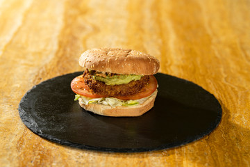 Hamburguesa sobre tabla de pizarra y madera