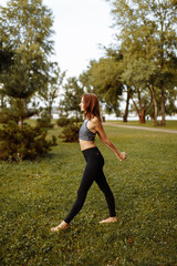 Beautiful girl doing a warm-up before yoga in the park.