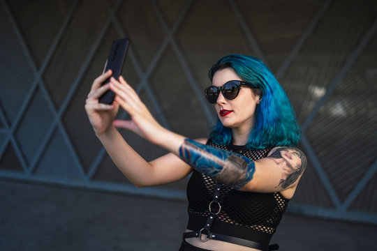 Chica alternativa con el pelo azul y tatuajes posando