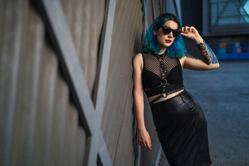 Chica alternativa con el pelo azul y tatuajes posando
