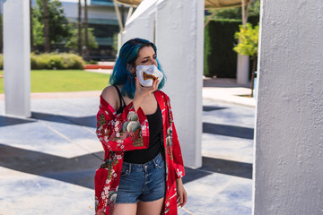 Chica alternativa con el pelo azul y tatuajes posando