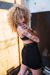 Chica rubia con rizos con estilo urbano posando
