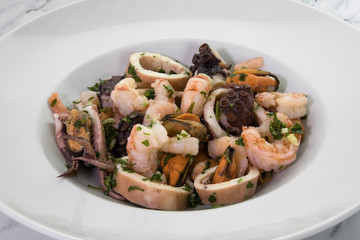 Gourmet. Traditional mediterranean seafood dish with Provencal condiment, garlic and parsley. Spicy shrimps, squid, prawns and mussels in a white dish.