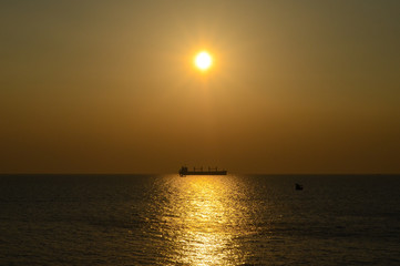 Silhouette cargo ship in the sea on the background of the sunset sky