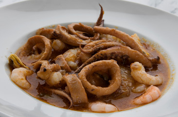 Gourmet. Dish presentation. Closeup view of a mediterranean shellfish stew with shrimps, prawns, scallops, squid, mussels and a spicy sauce. 