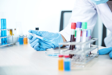 Doctor hold the pipette and drop the blue chemical liquid into a petri dish for research and analysis for treating viral and bacterial illness in a laboratory