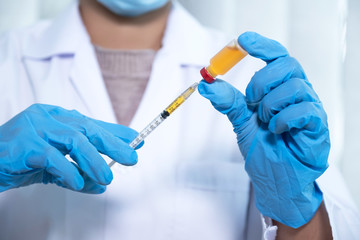 Doctors hold the syringe, vaccine, cure virus, bacteria and in there the yellow chemical liquid for research and analysis in a laboratory
