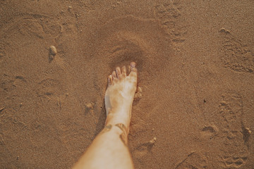 Pie medio enterrado en arena de la playa