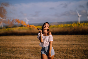 Chica feliz en campo con bomba de humo