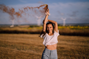 Chica feliz en campo con bomba de humo