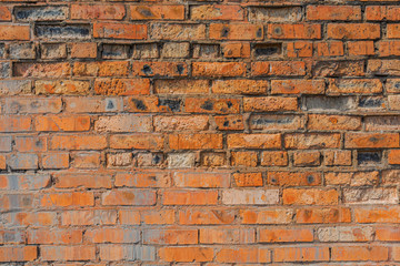 Old, antique wall of red destroyed bricks. The brickwork is made of bricks produced according to the old technology.